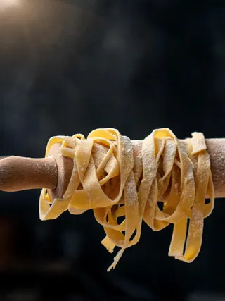 Nastri di pasta fresca infarinati appesi a un matterello