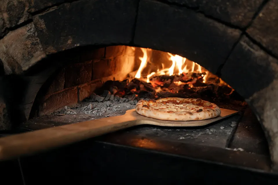 Pizza appena sfornata davanti al caldo bagliore del forno
